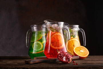 Set of colorful lemonades in jugs. On dark background