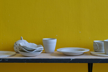 Unfinished clay pots on shelves as part of a ceramic pottery workshop. Creative studio potter. different ceramic dishware on wooden shelves.