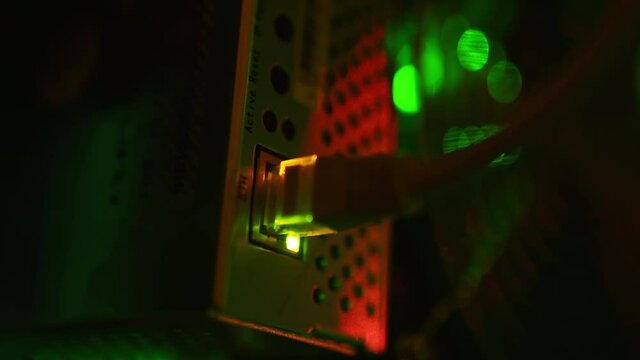 Macro. Ethernet cable rj-45 connectors plugs connected to bitcoin mining ASIC equipment in cryptocurrency farm. Internet plug in sockets of network boards blinking with lights in datacenter.
