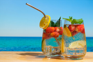 Hard seltzer cocktails. Chilled drinks, beautiful summer beach on background. Summer cocktails, beach bar concept.  - obrazy, fototapety, plakaty