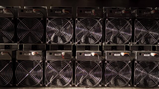 Bitcoin ASIC miners in warehouse. ASIC mining equipment on stand racks for mining cryptocurrency in steel container. Blockchain techology application specific integrated circuit units storage.