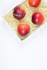 Zenith view. Group of nectarines inside a box. White background and copy space.