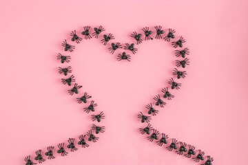 Creative composition with black spiders against a pink background. Minimal Halloween romantic love concept. Flat lay.