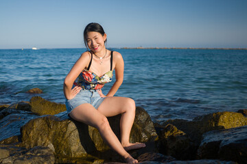 young Asian woman by blue sea -  happy and beautiful Chinese girl  enjoying holiday trip relaxed and cheerful at beach rock cliff during summer in tourist  travel concept