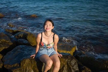 young Asian woman by blue sea -  happy and beautiful Chinese girl  enjoying holiday trip relaxed and cheerful at beach rock cliff during summer in tourist  travel concept