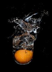 Chicken eggs thrown in a glass of water. Splash of water on a black background. 