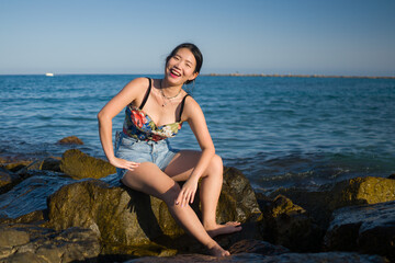 holidays lifestyle portrait of young Asian woman by the  sea -  happy and beautiful Korean girl  enjoying beach vacation trip relaxed and cheerful at beach rock cliff