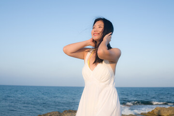 holidays lifestyle portrait of young Asian woman by the  sea -  happy and beautiful Korean girl  enjoying beach vacation trip relaxed and cheerful at beach rock cliff