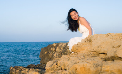 holidays lifestyle portrait of young Asian woman by the  sea -  happy and beautiful Korean girl  enjoying beach vacation trip relaxed and cheerful at beach rock cliff