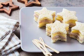 Christmas food - Star-shaped cheese and ham sandwiches on gray plate. Festive food concept.