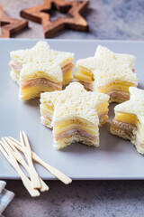 Christmas Snacks - Star-shaped cheese and ham sandwiches on gray plate. Festive food concept.