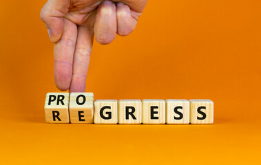 Regress or progress symbol. Businessman turns wooden cubes and changes the word 'regress' to 'progress'. Beautiful orange table, orange background, copy space. Business, regress or progress concept.