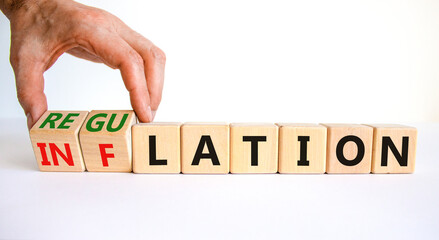 Inflation or regulation symbol. Businessman turns cubes and changes the word inflation to regulation. Beautiful white table, white background, copy space. Business, inflation or regulation concept.