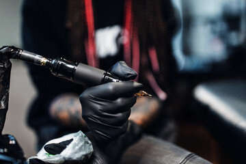 Female Hands In black Rubber Gloves Hold A Tattoo Machine in the tattoo studio
