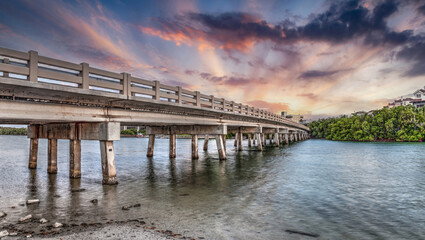Fototapeta premium Sunset sky over bridge over Hickory Pass leading to the ocean in Bonita Springs