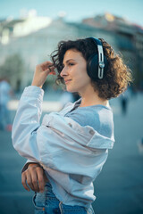 Portrait of a girl with curly hair dressed casually standing outdoors and looking away.