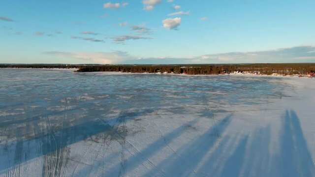 Fascinating speedy video from FPV drone flying over forest edge down to icy lake, original sound included. Northern Sweden, Umea, Stocksjo lake. First person view footage
