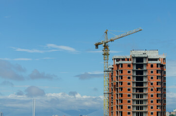 Tower cranes in action against the blue sky. Construction of new multi-storey buildings. A residential building is being built using a crane.