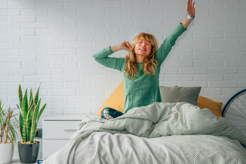 woman waking up with joy in the room with raised arms stretching