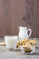 Oat milk in a cup, oatmeal and ears of corn on the table. Alternative to cow's milk. Vertical view