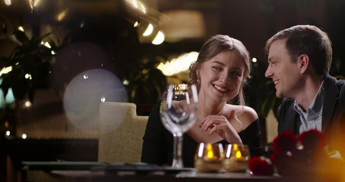 Caucasian man talking to his girlfriend during a romantic dinner at restaurant. Young couple enjoying their date and relaxing 4k footage