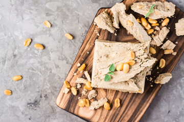 Pieces of sunflower and peanut halva and mint leaves on a cutting board on the table. Caloric oriental dessert. Top view. Close-up