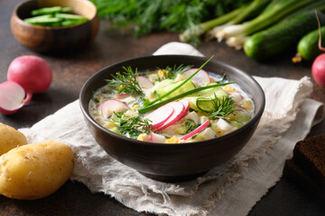 Cold okroshka soup with kefir. Freshness Russian okroshka made of summer chopped vegetables, cucumber, radish, potato, boiled eggs with herbs seasoned with kefir or airan, carbonated water. Close up
