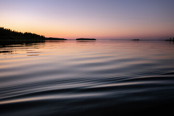 Midnight sea Sun in Northern Sweden during light Summer nights. Mirror like water surface, rose...