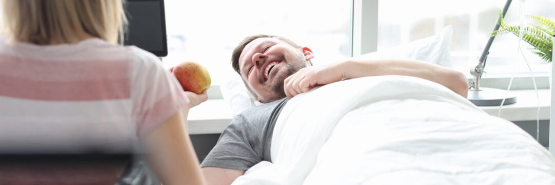 Relative visiting patient in hospital ward. Man lying in bed