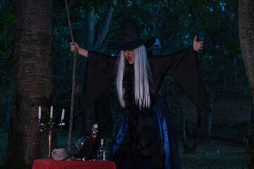 Woman in a witch costume posing in forest at twilight. Spells, magic and witchcraft.