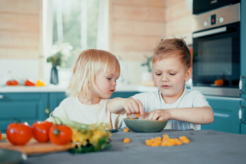 Boys children eat colored vegetables in the kitchen from a plate. Happy time happy mood. Play together friends and brothers