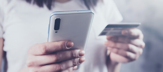 girl holding a phone and a bank card in her hands