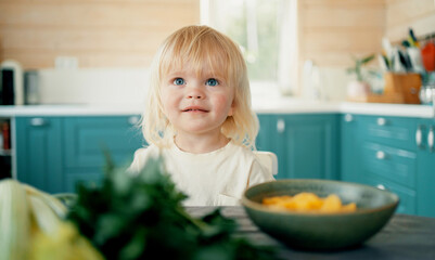 Portrait of a cheerful cute child playing fun games in the kitchen in the apartment with fresh vegetables. Good children's mood weekend holidays. Country house in the village.