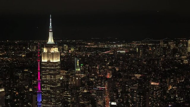 AERIAL: Breathtaking drone point of view of the picturesque New York City skyline at midnight. Spectacular flying view of the illuminated skyscrapers and streets of the famous Big Apple at night.