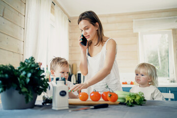 Obraz na płótnie Canvas Mom and baby blonde prepare food from fresh vegetables in the kitchen. Children in the kitchen. Happy time together with your family, good mood.