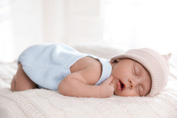 Adorable newborn baby sleeping on white knitted plaid