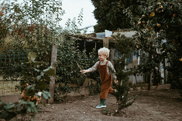 Blond kid in the garden running after a chicken