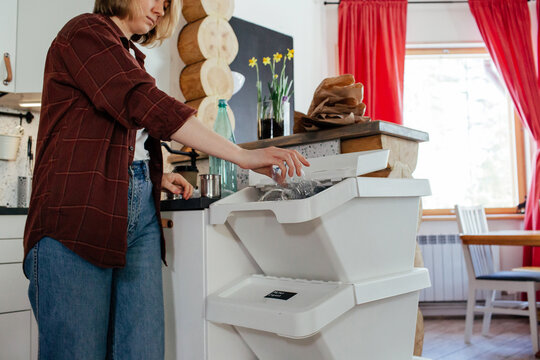 Housewife throwing plastic bottle into trash bin for recycling