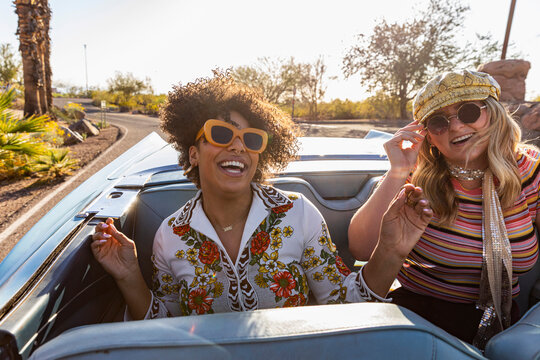 Happy Friends riding in the back of Convertible car in Arizona on road 