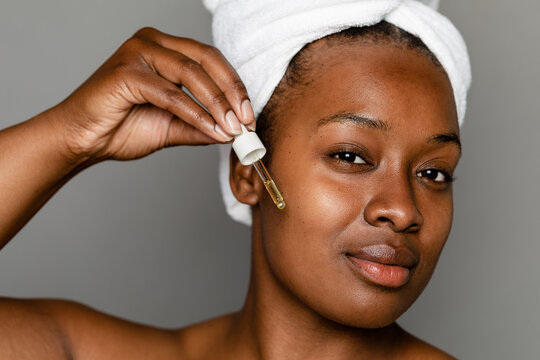 Black Woman Using Applicator To Apply Facial Oil