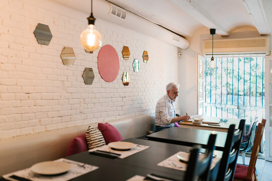 Busy male entrepreneur taking notes during work in cafe