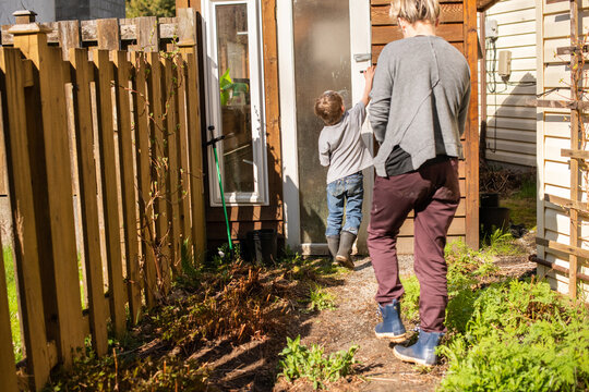 Young son and mom entering a small greenhouse.
