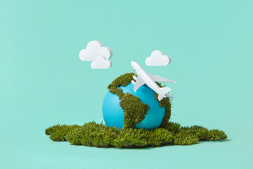 Earth globe with green moss, plane model and clouds