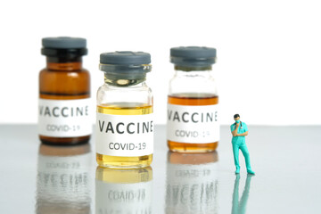 Miniature people toy figure photography. Vaccine alternative choice concept. A nurse standing in front of ampoule bottle.