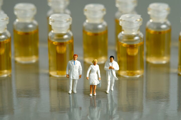 Miniature people toy figure photography. Vaccination distribution concept. A group of doctor walking in front of ampule vaccine vial.