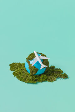 Earth globe with green moss and plane miniature