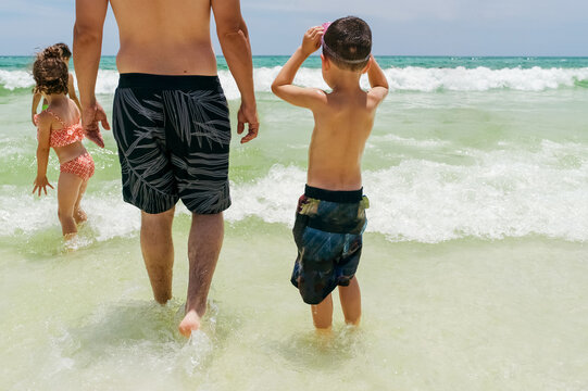 Father and his kids walking in the ocean. 