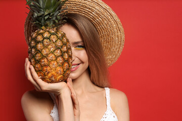 Young woman with fresh pineapple on red background, space for text. Exotic fruit