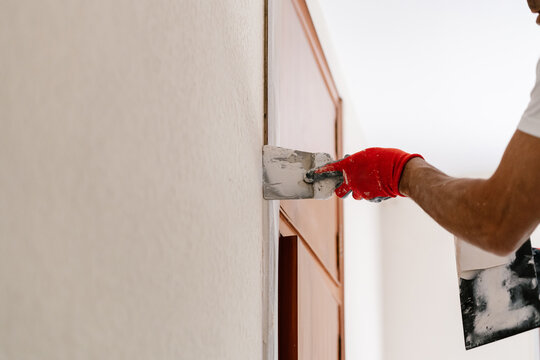 Anonymous mason's hand performing repairs on a house.