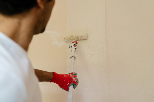 Anonymous mason using a paint roller to paint the wall